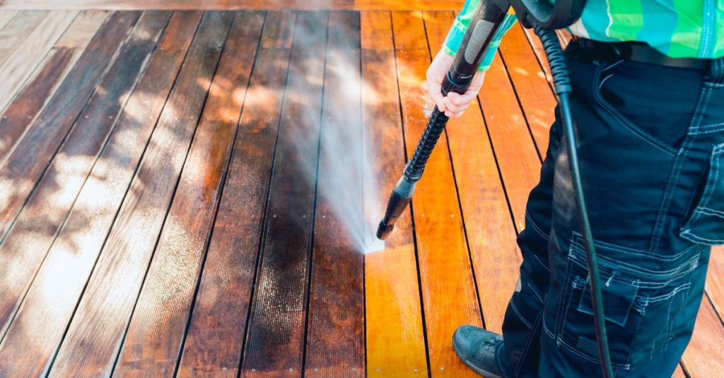 A professional worker power washing a deck