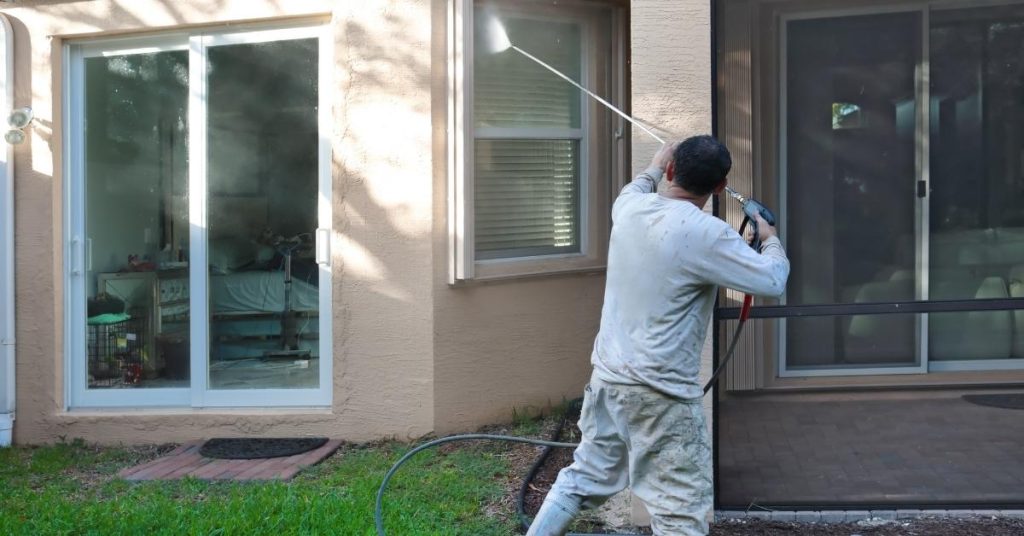 a man carefully power washing the exterior of a house