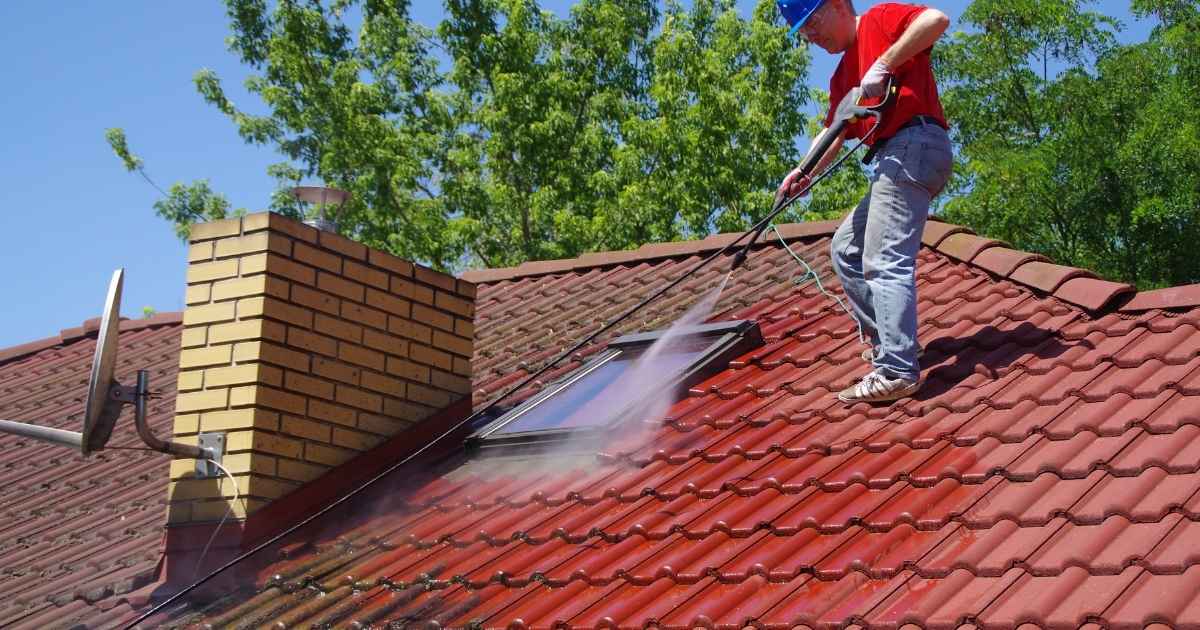 A man cleaning roof by pressure washing